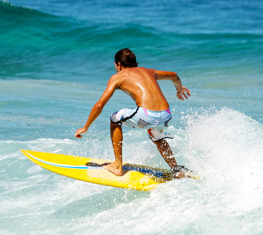 Young guy surfing the wave in a sunny day
