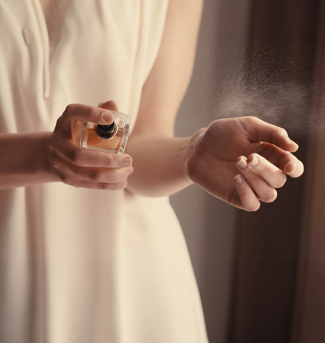 Beautiful young woman with bottle of perfume at home, closeup